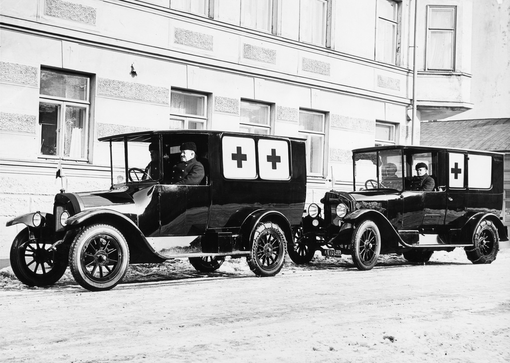 Ambulanssiautoja Vironkadulla Helsingissä. Vironkatu 1. Kuvassa palolaitoksen kaksi ensimmäistä ambulanssiautoa. Vasemmalla Finlandia merkkinen ambulanssi, joka tehtiin v 1923 palokuntaan hankitusta Finladia kuorma-autosta, jonka huolto numrooli 7. ambulanssiksi muutoksen jälkeen auto huoltonumerokseen 20. Muutostyö valmistui v1925. Takimmainen auto on Daimler-benz ambulanssi vuodelta 1923. Se ostettiin valmiina ambulanssina saksasta. huolto numero 19.