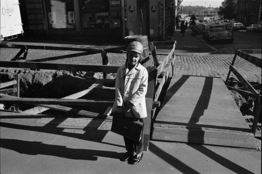 Liisankatu 9. Pieni koulutyttö seisomassa laukku kädessä katutyömaan edessä Liisankadun ja Meritullinkadun kulmassa. Näkymä Maurinkadun suuntaan.
