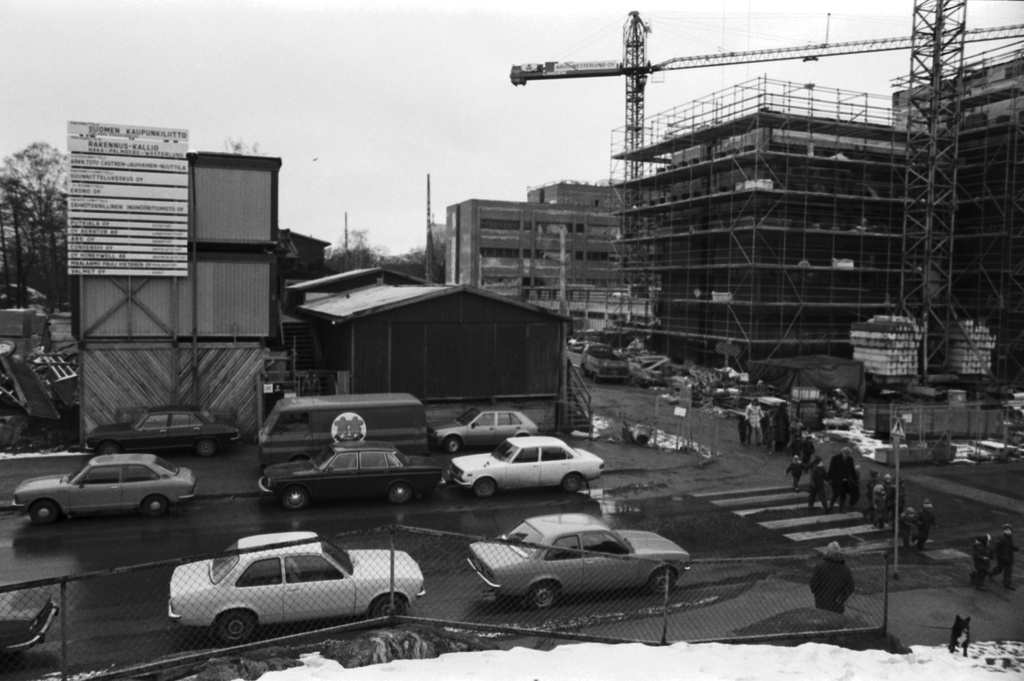 Ensi linja 3. Suomen Kaupunkiliiton toimitalon (Kuntatalon) rakennustyömaa. Näkymä Ensi linjan ja Eläintarhantien kulmassa olevilta kallioilta luoteeseen. Vasemmalla työmaaparakkeja, oikealla rakennustelineiden peitossa oleva toimitalo.