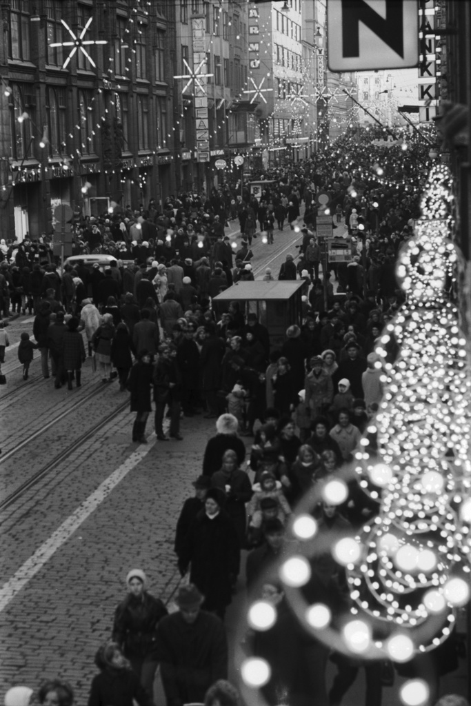 Kluuvi, Aleksanterinkatu. Joulukatu on avattu - valot ovat syttyneet. Ihmisiä kävelemässä sankoin joukoin Aleksanterinkatua. Kadun 12.6.1970 alkanut kävelykatukokeilu päättyi 8.1.1971. Kuva otettu Kuusisen talon parvekkeelta Kluuvikadun suuntaan.