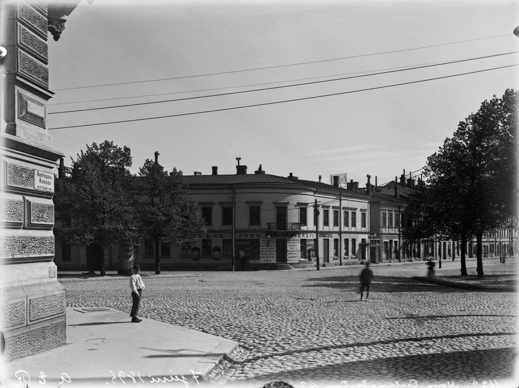 Pohjois-Esplanaadikatu (=Pohjoisesplanadi) 43 ja 41 (nyk. 41) Antinkadun (=Lönnrotinkatu) ja Heikinkadun (=Mannerheimintie) risteyksestä nähtynä. Kulmassa John Tourunen & Co:n liiketiloja.