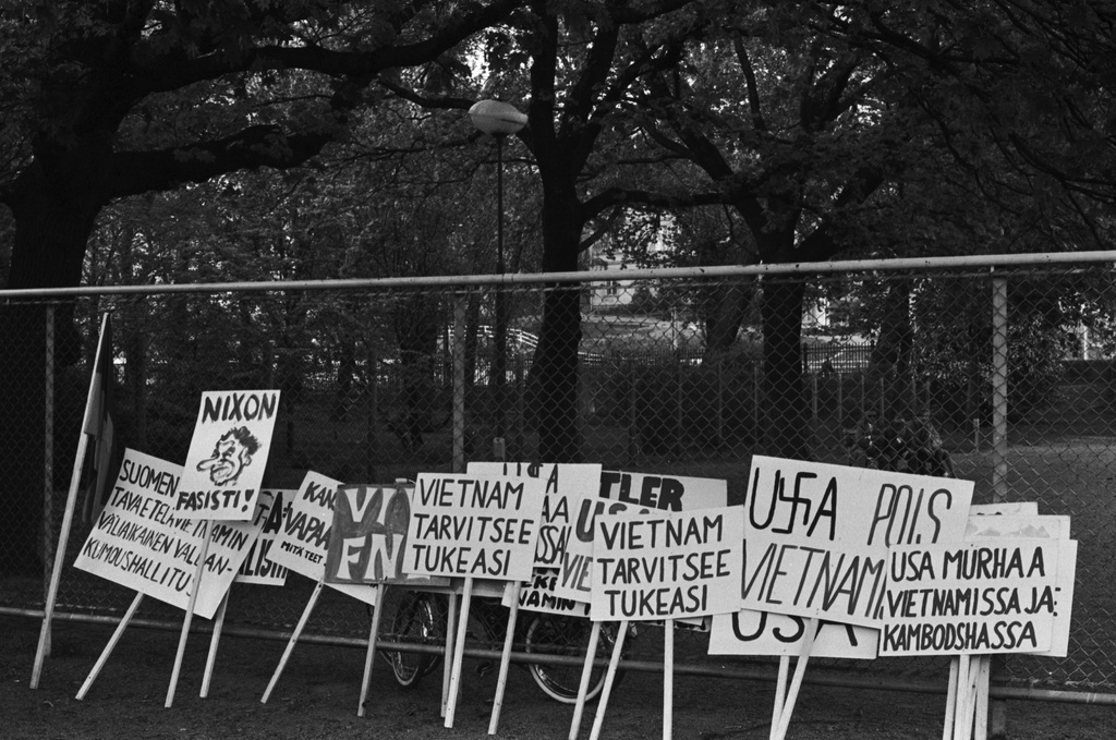 Kaisaniemenpuisto. Vietnamin sodan vastaisen mielenosoituksen kylttejä nojaamassa verkkoaitaan Kaisaniemenpuistossa.