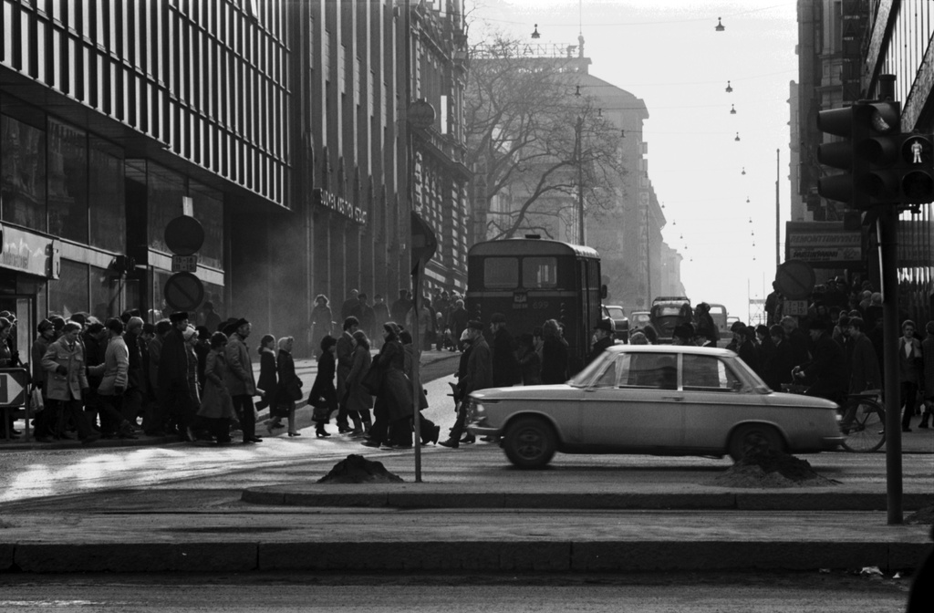 Kamppi, Lönnrotinkatu. Sankoin joukoin jalankulkijoita sekä autoja ruuhka-aikaan Lönnrotinkadun ja Mannerheimintien risteyksessä. Keskellä Helsingin liikennelaitoksen linja-auto HKL 699 linjalla 57, etualalla kiihdyttää BMW. Näkymä Pohjoisesplanadin päästä lounaaseen.