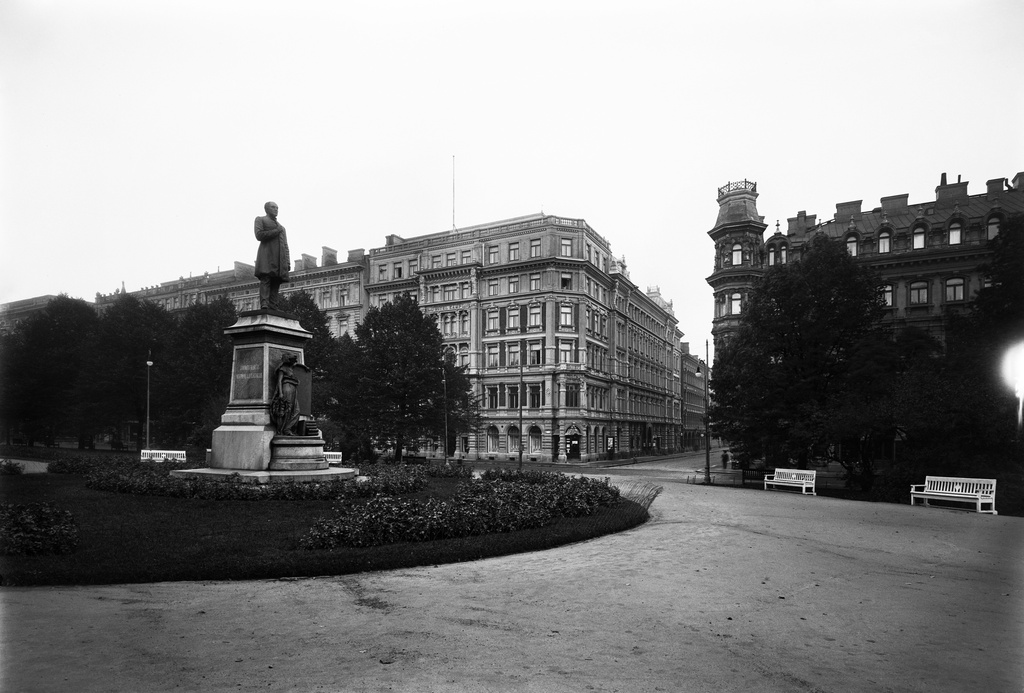 Runebergin patsas Runebergin esplanadilla. Patsaan teki Walter Runeberg, pystytettiin 1885.Takana vas. Pohjoisesplanadi 29 (- Kluuvikatu 2), hotelli Kämpin talo. Sen suunnitteli Theodor Höijer ja se valmistui 1887.Oik.on Pohjoisesplanadi 25-27 (-Kluuvikatu 1), Grönqvistin talo. Senkin suunnitteli Theodor Höijer ja se valmistui 1883.