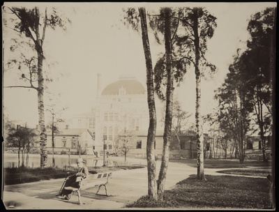 Kaisaniemen puisto, mies istuu penkillä. Vasemmalla joutsenlampi, taustalla Kansallisteatteri ja Villensaunan (Wilhelmsbad) kylpylän puurakennuksia.  duplicate photo