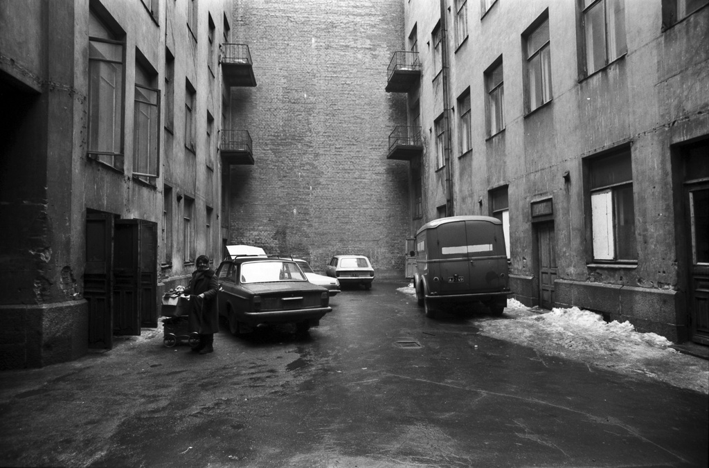 Fabianinkatu 8. Vanha nainen rattaineen seisomassa kerrostalon pihalla Fabianinkadulla.