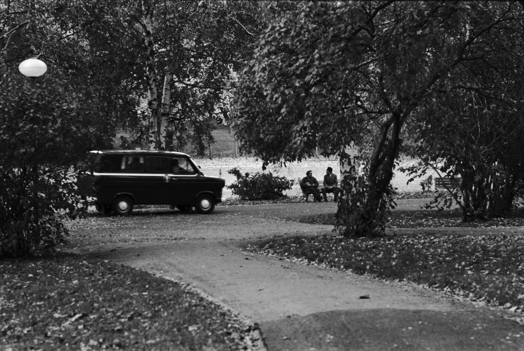 Kluuvi, Kaisaniemenpuisto. Näkymä syksyisestä Kaisaniemenpuistosta. Puistokäytävällä ajaa poliisiauto, penkillä istuu kaksi miestä.
