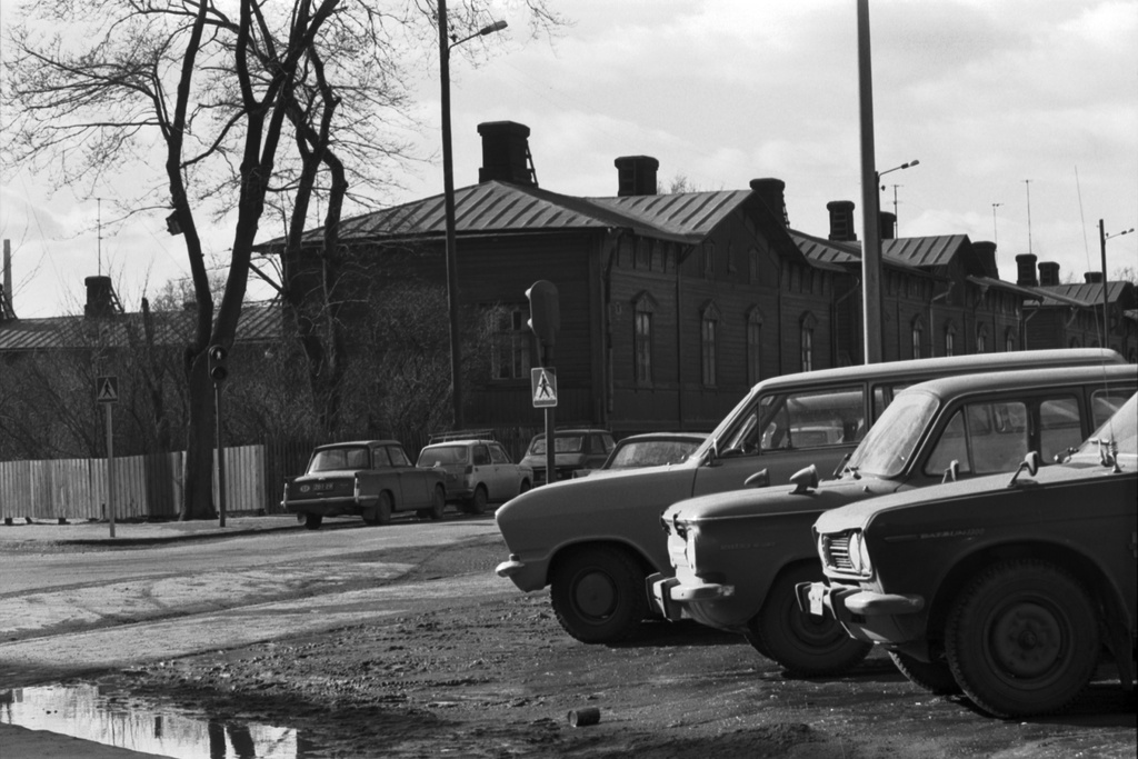 Kamppi, Lastenkodinkatu. Näkymä auton ikkunasta Ruoholahdenkadulta Lastenkodinkadun kulmalta länsilounaaseen. Etualalla pysäköityjä autoja. Taustalla puutaloja, Ruoholahden ns. sadan markan villoja.