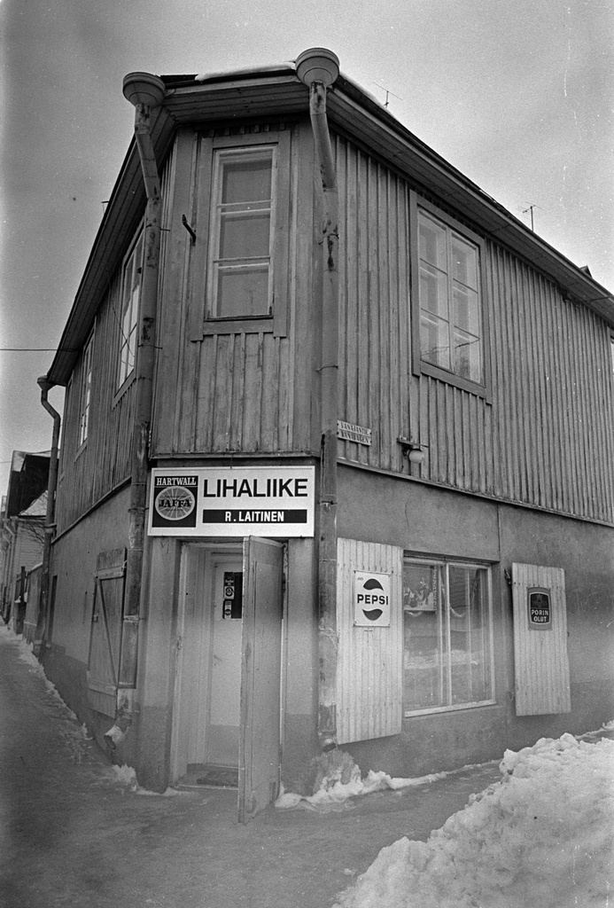 Lihaliike R. Laitinen Vallilantien ja Vanajantien kulmassa sijaitsevassa puutalossa Puu-Vallilassa. Liikkeen kyltissä ja ikkunaluukuissa on juomamainoksia.