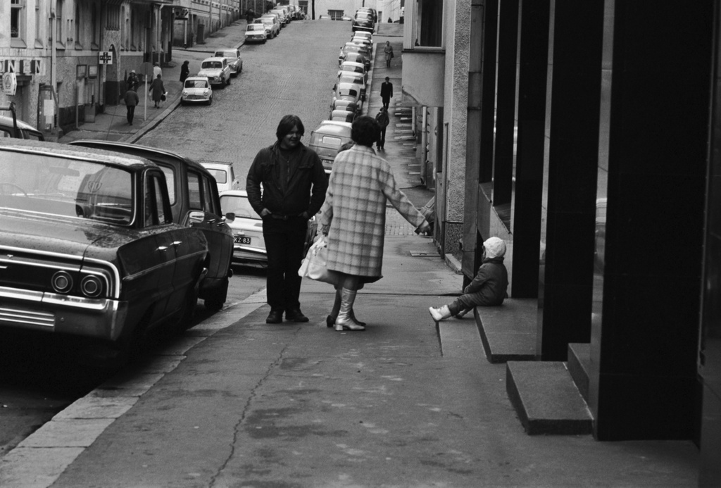 Kruununhaka, Meritullinkatu. Nuorehko mies, iäkkäämpi nainen ja sisäänkäynnin portaalla istuva pieni lapsi Meritullinkatu 21:n edessä. Näkymä Liisankadulle päin.