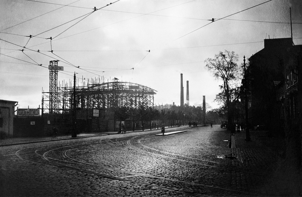Messuhallin (= Töölön kisahalli) rakennustyömaa pohjoisesta 1935. Turuntie 9 (= Mannerheimintie 17). Taustalla Töölön Sokeritehtaan piippuja.