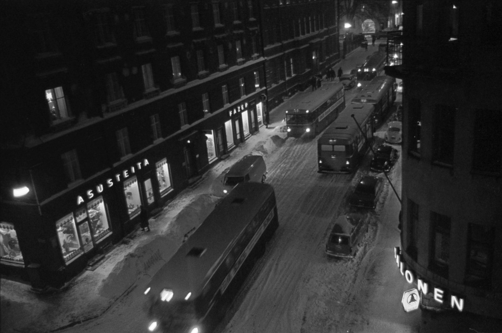 Liisankatu. Busseja, autoja ja jalankulkijoita talvi-iltana lumisella Liisankadulla Meritullinkadun risteyksessä. Kuvattu Liisankatu 7:n neljännen kerroksen ikkunasta Mariankadun suuntaan.