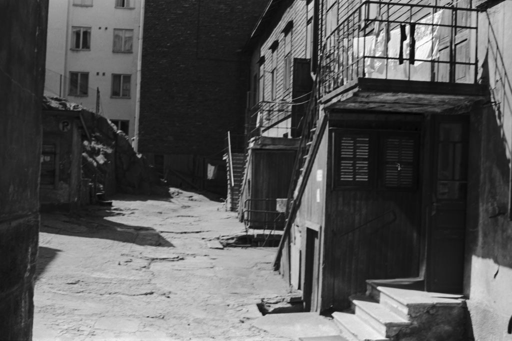 Fleminginkatu 16. Näkymä portilta Fleminginkatu 16:n pihalle. Oikealla kaksikerroksinen puutalo.
