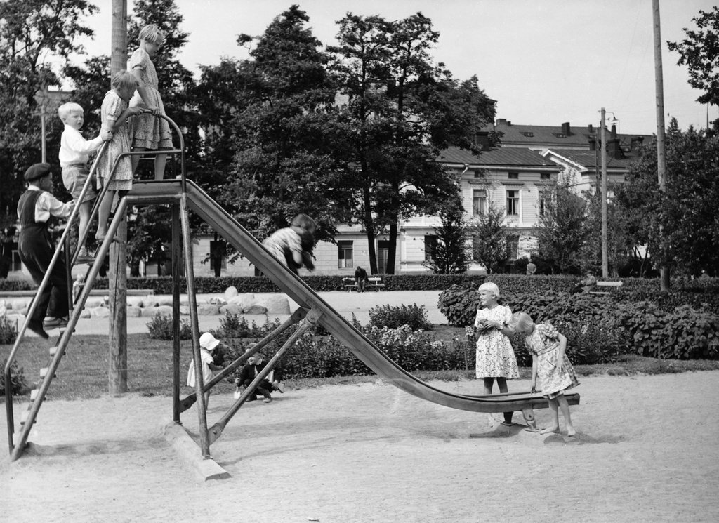 Lapsia liukumäessä Tehtaanpuistossa, takana Sepänkatu 9.