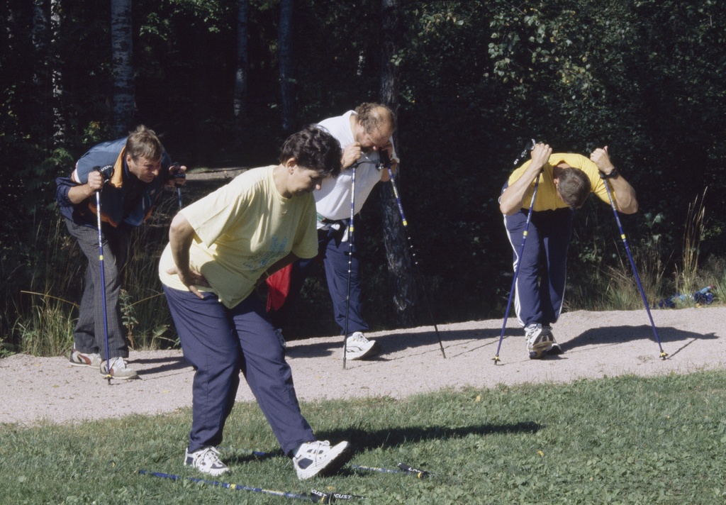 Sauvakävelijät venyttelevät. Pirkkolan urheilupuisto.