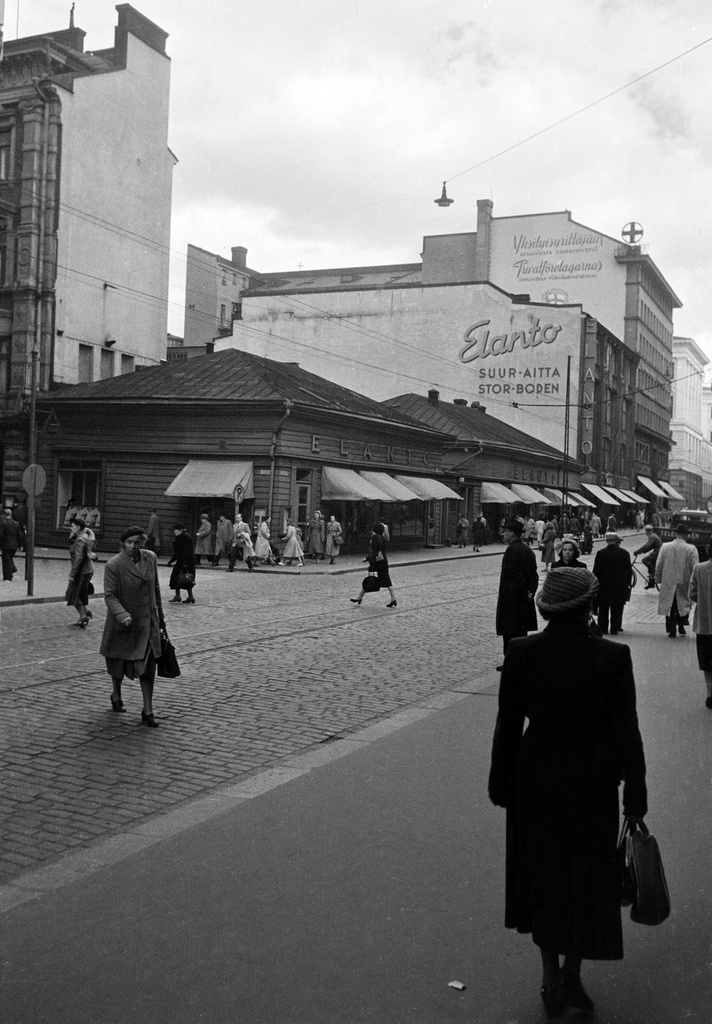 Aleksanterinkatu 9. - Kluuvikatu 5. Elannon myymälä ja Elannon suur-aitta. Puurakennukset purettiin syksyllä 1950 ja paikalle rakennettiin Elannon tavaratalo.
