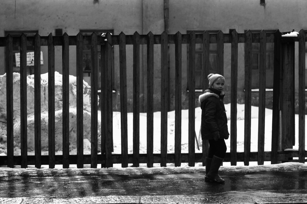 Lapinlahdenkatu 6. Tyttö kävelemässä aidan vieressä Lapinlahdenkadulla kevätauringon sulattaessa lumikinoksia. Taustalla Lapinlahden ns. apukoulu.