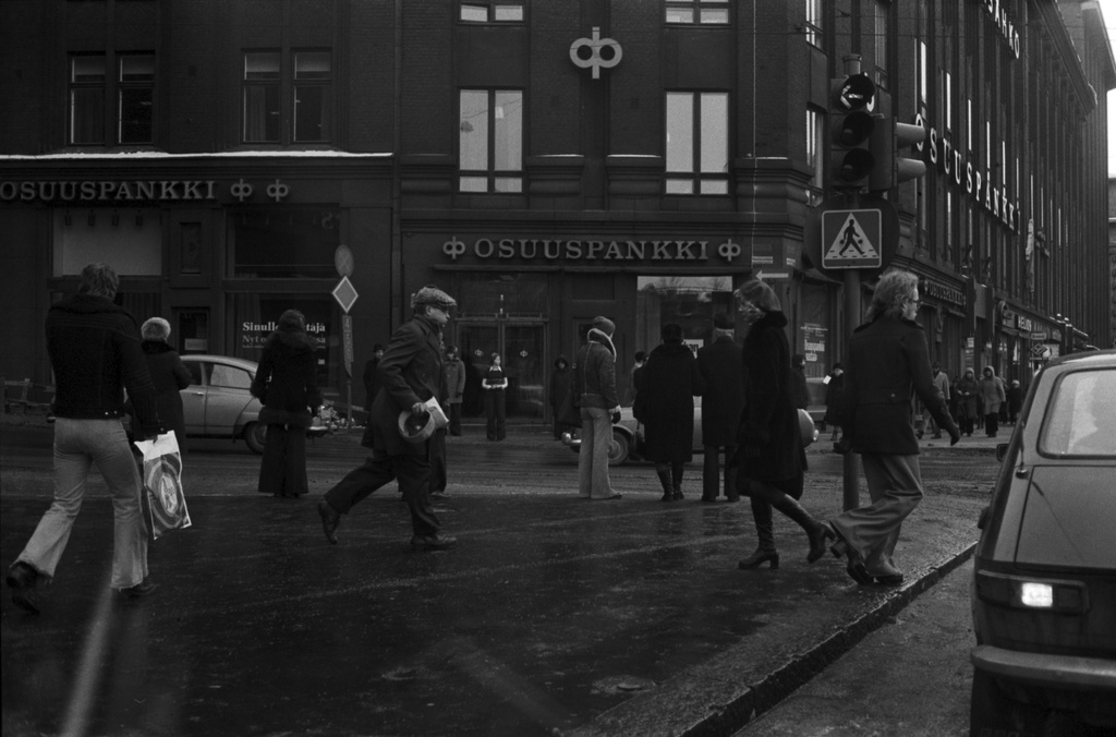 Kaisaniemenkatu 1. Kiireisiä jalankulkijoita sateisella säällä Osuuspankin kulmalla Kaisaniemenkadun ja Mikonkadun kulmassa. Kuvattu auton etuikkunasta.
