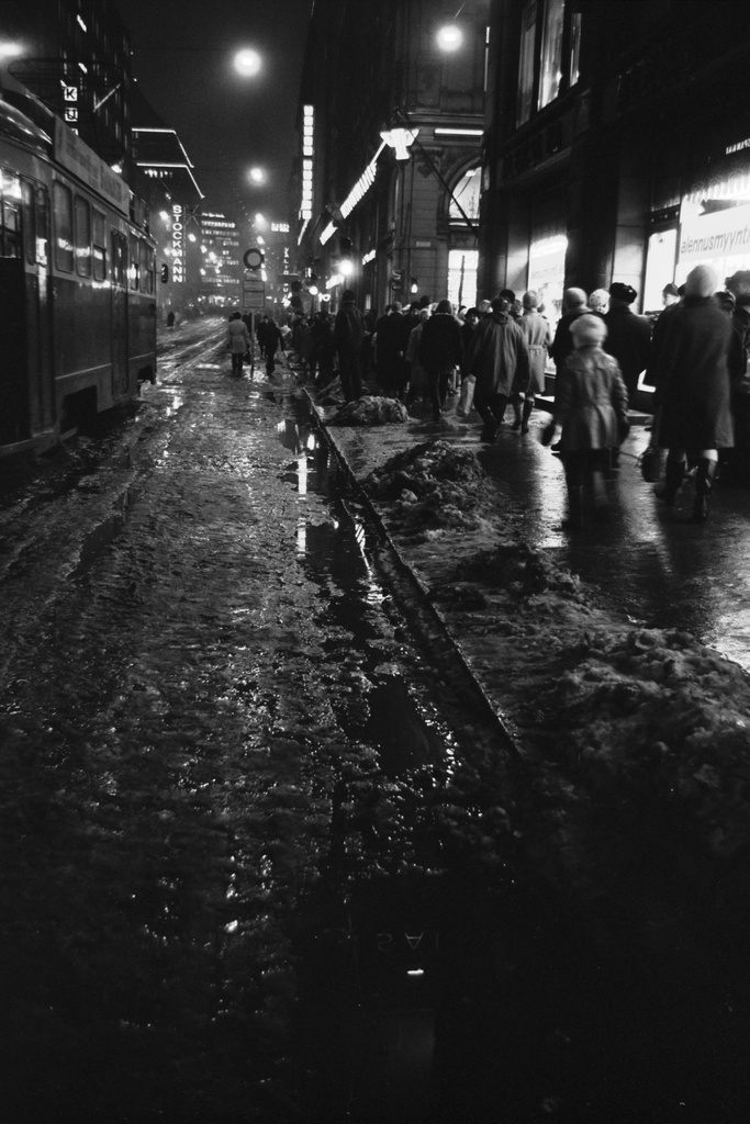 Kluuvi, Aleksanterinkatu. Näkymä ruuhka-aikaan talvipäivän pimetessä sumuiselta, loskaiselta Aleksanterinkadulta Mikonkadun kulmasta Mannerheimintien suuntaan. Kaupungin valot peilautuvat lätäköistä.