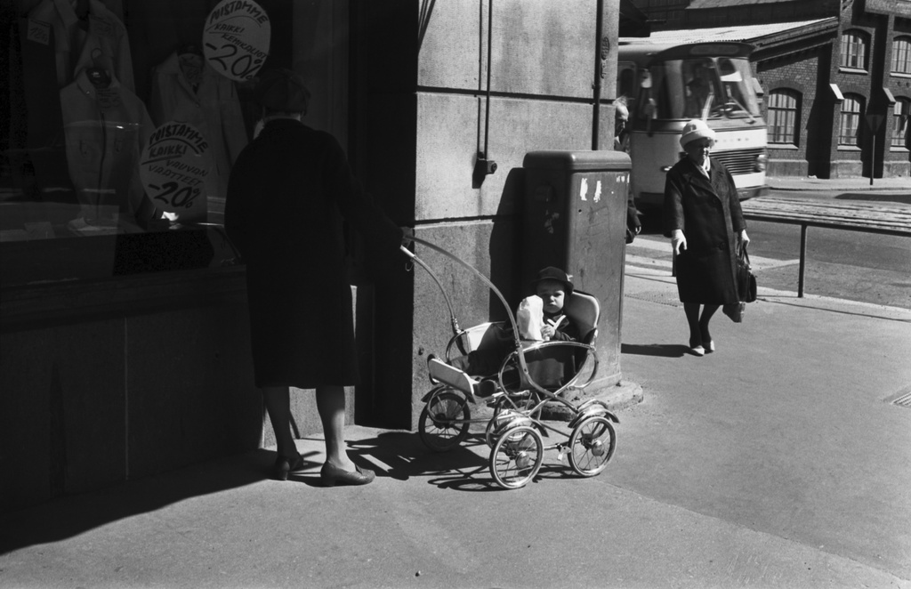 Kolmas linja 1. Nainen lastenrattaiden kanssa katsomassa asusteliikkeen näyteikkunaa Kolmannella linjalla Hämeentien kulmassa.