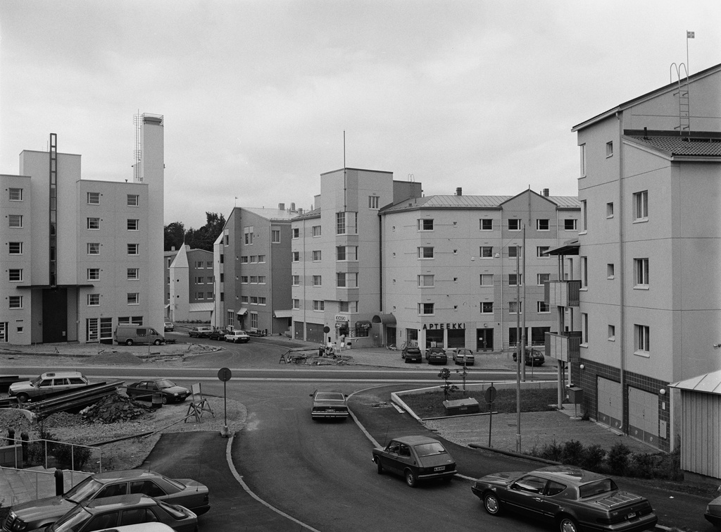 Pikku Huopalahti. Näkymä Kemiönkujalta etelään kohden Paimionkujaa. Vasemmalla Mannerheimintie 168. Sen oikealla puolella Velkuanpolku 2, 1, sekä Paimionkuja 1. Rakennus kuvan oikeassa laidassa on Korppaanmäentie 3. Kemiönkujalla pysäköidyt henkilöautot oikealta vasemmalle lukien: Mercury Cougar, Fiat 127, Chevrolet Caprice Classic.