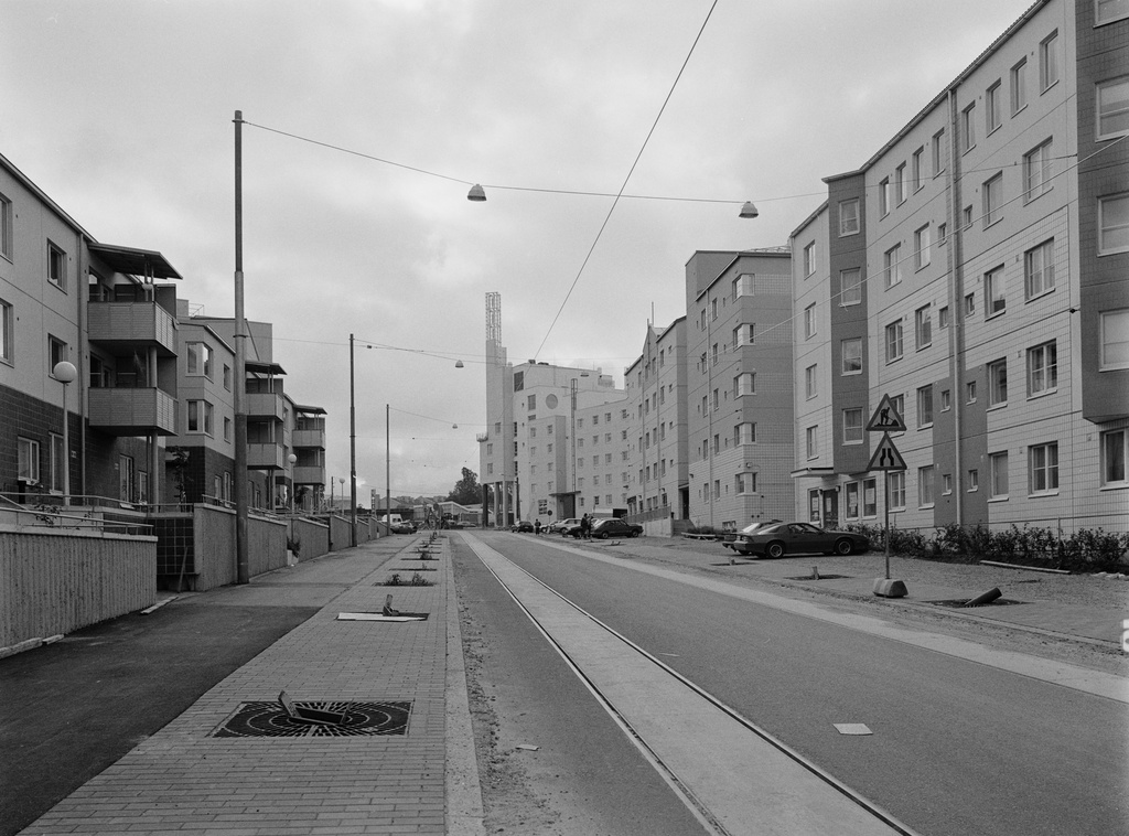 Pikku Huopalahti. Vasemmalla Korppaanmäentie 5, 3.  Oikealla Tilkankatu 2,  Korppaanmäentie 6,  Paimionkuja 1. Tien oikeassa reunassa pysäköityjä henkilöautoja. Lähimpänä kameraa Chevrolet Camaro, sen takana Chevrolet Beretta. Edempänä Fiat 127.