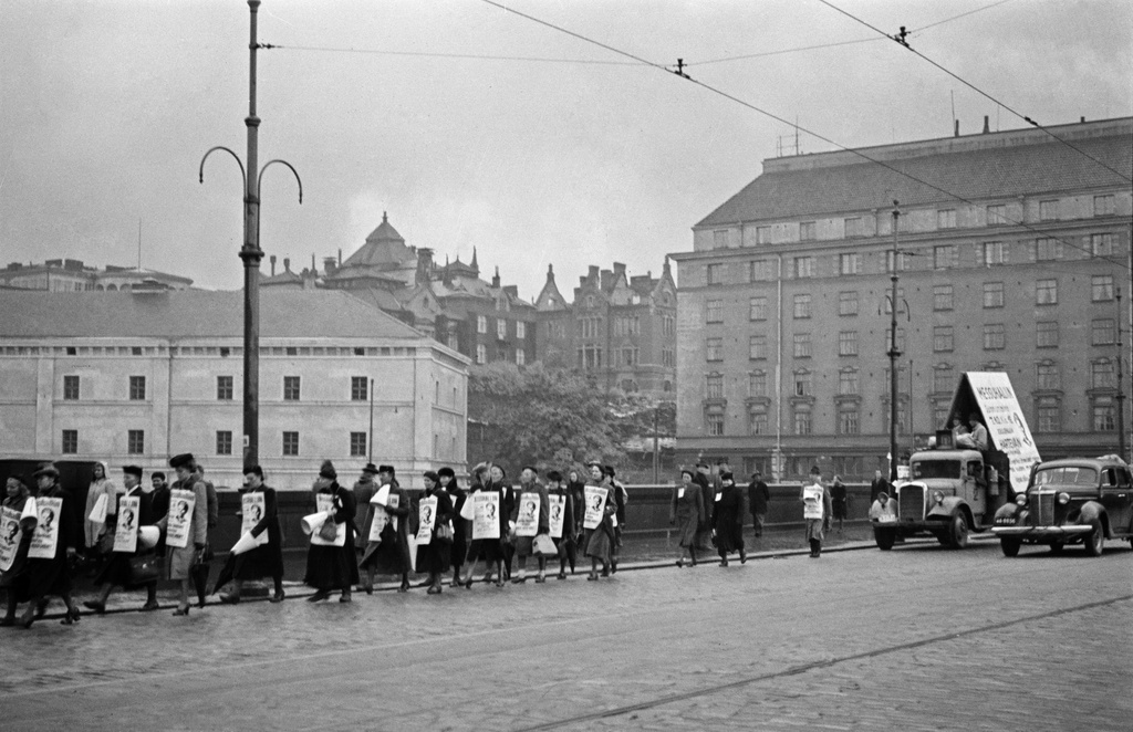 Jehovan todistaja, insinööri Kaarlo Hartevan esitelmää mainostava kulkue. Miehiä ja naisia mainos- ja tekstikylttien kanssa Pitkälläsillalla, taustalla Siltavuorenranta 16, 18 (Unioninkatu 45).