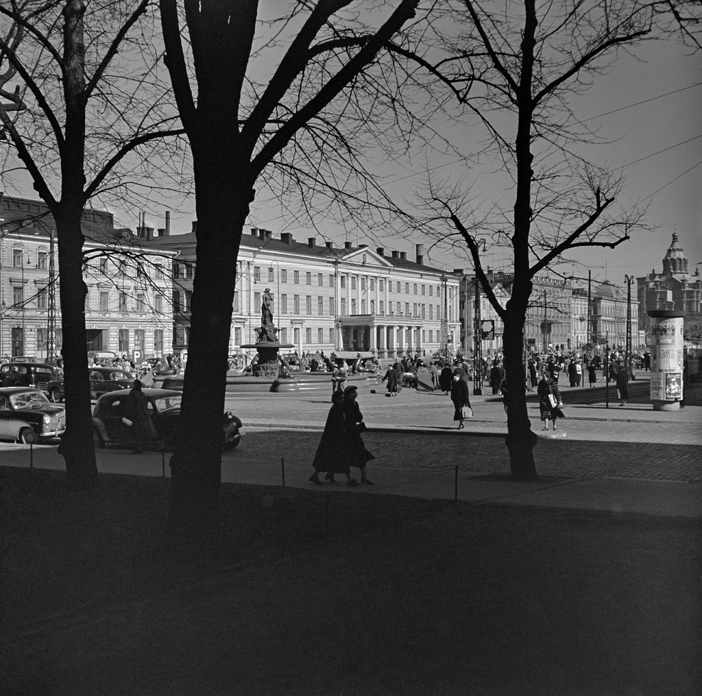 Edessä jalankulkijoita Unioninkadulla, takana Havis Amanda, Kauppatori. Takana vas.  Pohjoinen Esplanaadikatu (=Pohjoisesplanadi) 15 ja 11-13 (Kaupungintalo). Taustalla oik. Uspenskin katedraaali.