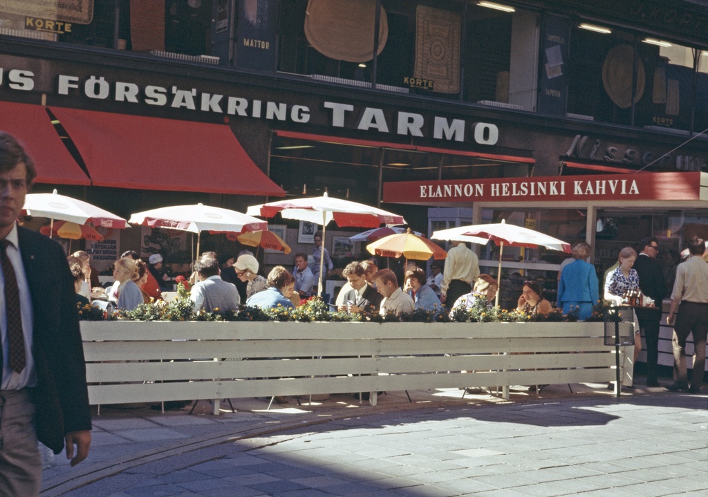 Elannon katukahvilassa istuskelijoita Kävely-Aleksilla, Aleksanterinkatu 9 edessä.