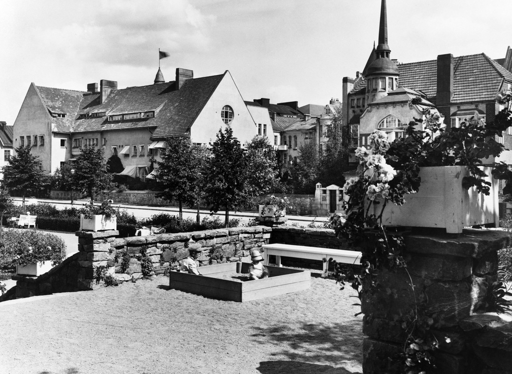 Eiran puisto. Lapsia hiekkalaatikolla kiviaidan vieressä. Takana Laivurinkatu 29, 27, 25, 23.