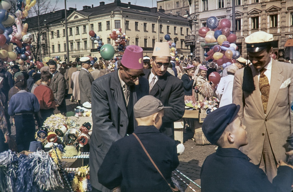 Vapputavaroiden myyjiä ja ihmisiä Kauppatorin vapputorilla. Taustalla Pohjoisesplanadi 17 ja 19.