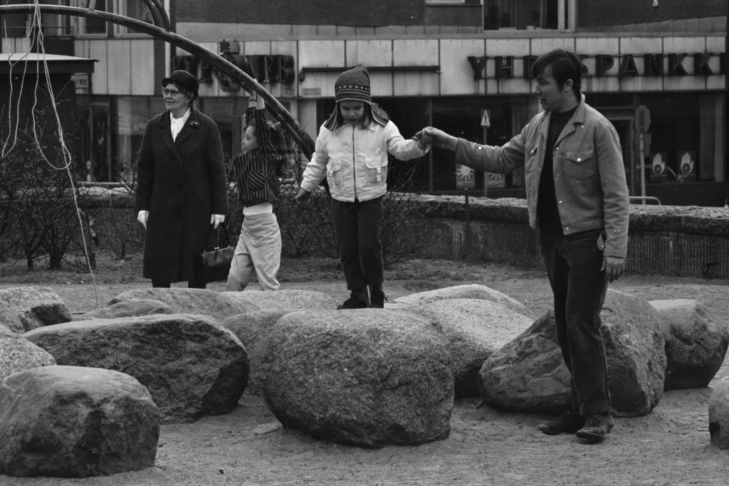 Karhupuisto. Mies taluttamassa tyttöä kivillä Karhupuistossa.