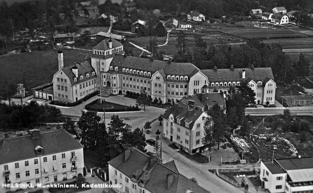 Hollantilaisentie (aik. Linnallé, Linnantie) 11, Munkkiniemi. Kuvan keskellä Eliel Saarisen suunnittelema Kadettikoulu, joka valmistui 1918. Rakennuksessa toimi ensin Munkkiniemen pensionaatti ja vuodesta 1924 Kadettikoulu. Se oli osa Saarisen Munkkiniemi-Haaga -suunnitelmaa, toinen Munkkiniemeen toteutuneista rakennuksista (toinen on rivitalo osoitteessa Hollantilaisentie 12-20). Oikeassa alakulmassa näkyy osa ravintola Golf Casinoa, joka paloi vuonna 1941. Munkkiniemi kuului vuodesta 1920 lähtien Huopalahden kuntaan, joka puolestaan liitettiin Helsingin kaupunkiin 1946.