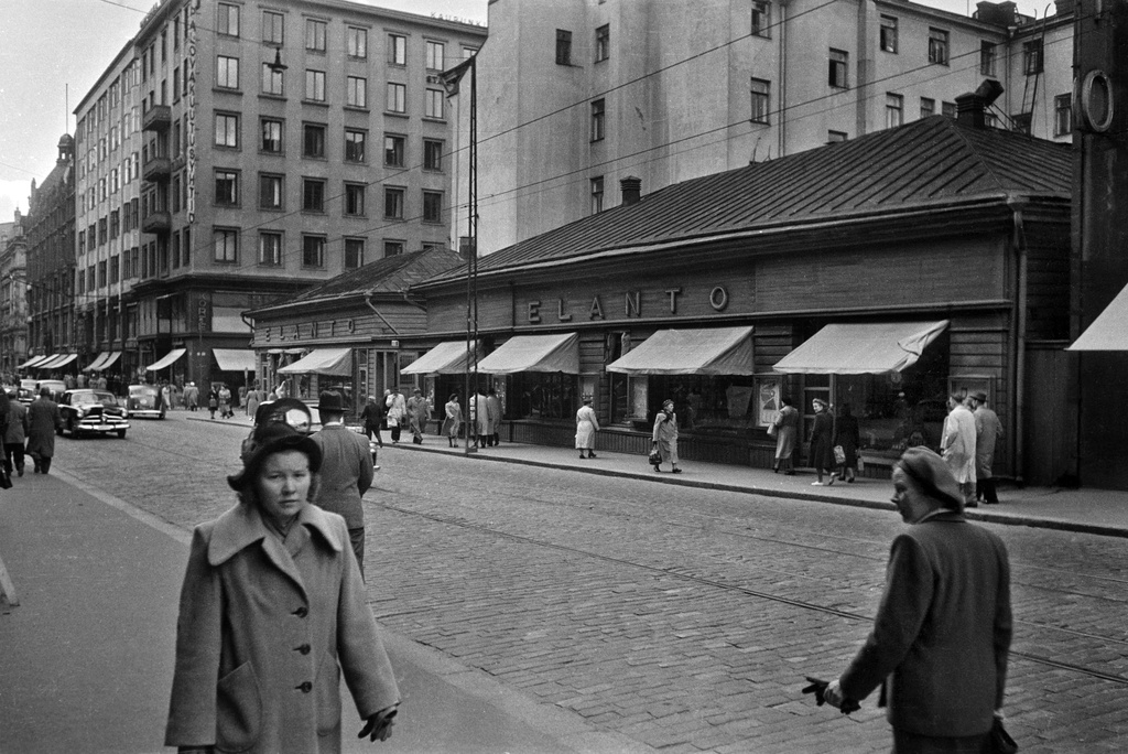 Aleksanterinkatu 13 - 9. - Kluuvikatu 5, 6. Näkymä Aleksanterinkatua länteen. Elannon myymälä. Puurakennukset purettiin syksyllä 1950 ja paikalle rakennettiin Elannon tavaratalo.