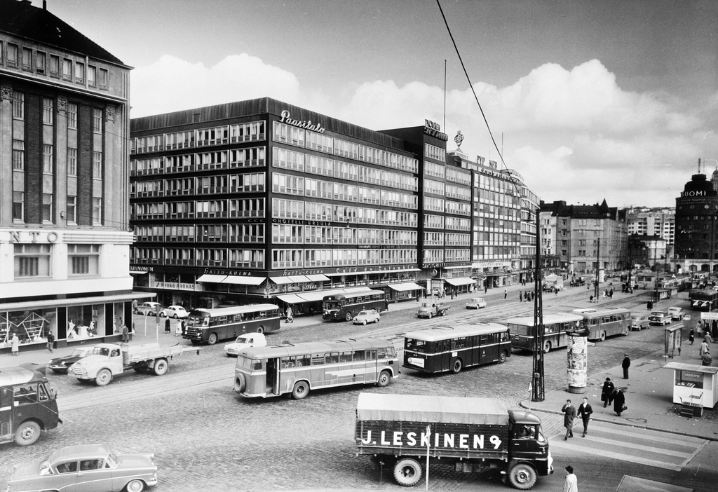 Siltasaarenkatu 12, 14. Keskellä Paasitalo, jossa sijaitsivat seuraavat yritykset: Hattu-Kulma, Kenkä Ahokas, Hotelli Ursula, Café de Colombia, Työväen Säästöpankki, PYP (Pohjoismaiden) Yhdyspankki ym. Etualalla J. Leskinen Oy:n kuorma-auto. Vilkasta liikennettä, busseja.