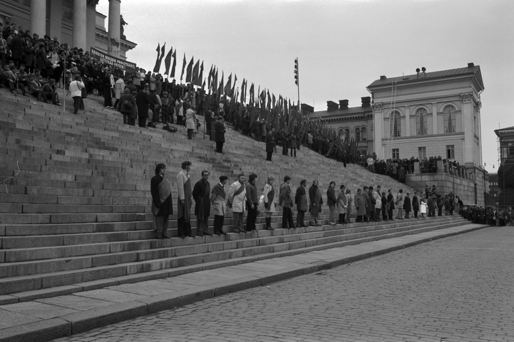 Hallituskatu 7. Ihmisiä, joilla airutnauhat seisomassa Tuomiokirkon alaportailla työväen vappujuhlassa 1.5.1972. Yläportailla ihmisiä lippujen kanssa.