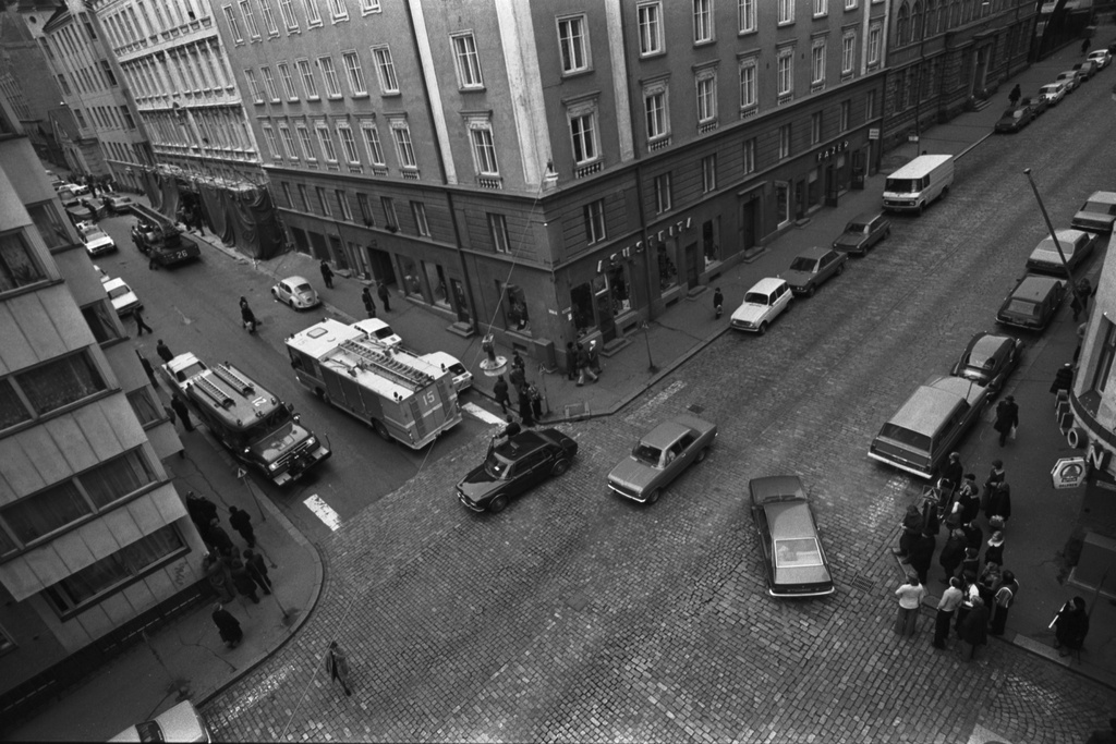 Liisankatu 4, 6. Meritullinkatu 22, 20. Pelastusmiehistö valmistautuu Meritullinkatu 20:n katolle kiivenneen miehen pelastustoimiin. Ihmisiä seuraamassa kadulla taphtumaa Liisankadun ja Meritullinkadun kulmassa. Kuvattu Liisankatu 7:n neljännen kerroksen ikkunasta.