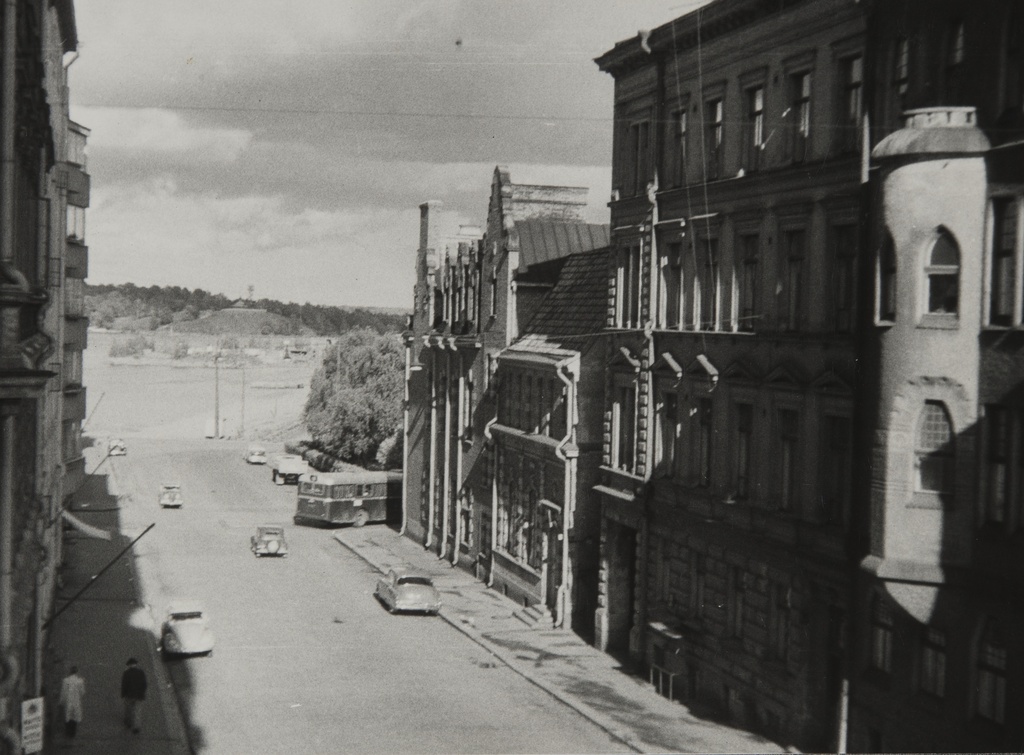 Katunäkymä Liisankatu 9:n ikkunasta. Oikealla Liisankatu 2 ja 4. Taustalla Tervasaari. Kadulla muutama jalankulkija ja autoja pysäköityinä.