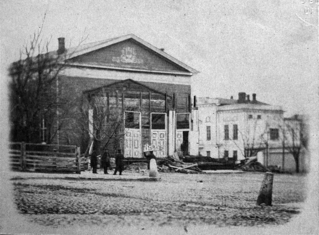 Helsingin ensimmäinen teatteri Esplanadi. Sisäänkäyntiä korjataan. Teatterin ed. vas. Edvard Bergh, Carl Robert Mannerheim, Julius Krohn, kesk. kantaa kipsikuvia päänsä päällä Pasquito Pera. Puurakennuksen piirsi intendentti Carl Ludvig Engel. Teatteri rakennettiin Esplanadin Erottajan puoleiseen päähän 1826-27.  Avajaisnäytös oli 19.3.1827. 19.2.1861 rakennus huutokaupattiin ja siirrettiin Arkadian huvila-alueelle missä toimi v:een 1902 Arkadia-teatterina.