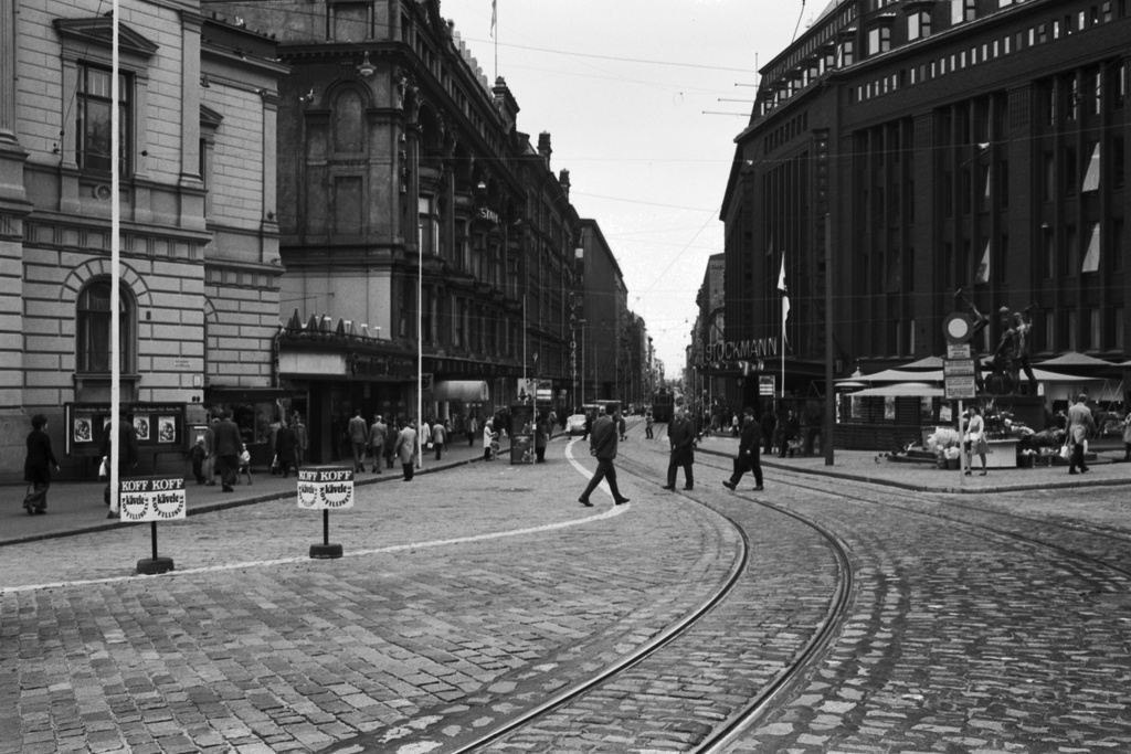 Aleksanterinkatu 23, 52. Näkymä Aleksanterinkadulle Mannerheimintien suunnalta kävelykatukokeilun aikoihin. Vasemmalla Vanhan ylioppilastalon edestä lähtevä valkoinen viiva, jolla on merkitty kävelyalue ajoradalla. Oikealla Stockmannin tavaratalo.