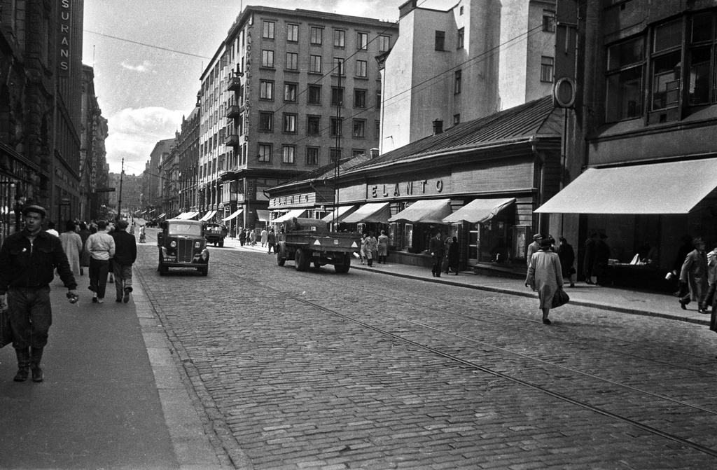 Aleksanterinkatu 9 - 11, 38. - Kluuvikatu 5, 6. Näkymä Aleksanterinkatua länteen. Elannon myymälä. Puurakennukset purettiin syksyllä 1950 ja paikalle rakennettiin Elannon tavaratalo.