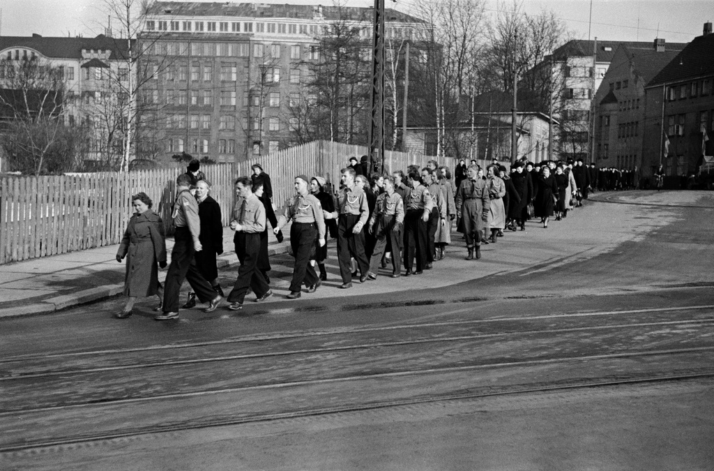 Miina Sillanpään hautajaiset. Hautasaatto kääntymässä Kalmistokadulle (=Mechelininkatu), etualalla ryhmä pioneereja. Taustalla Eteläinen Rautatiekatu 18, 20.