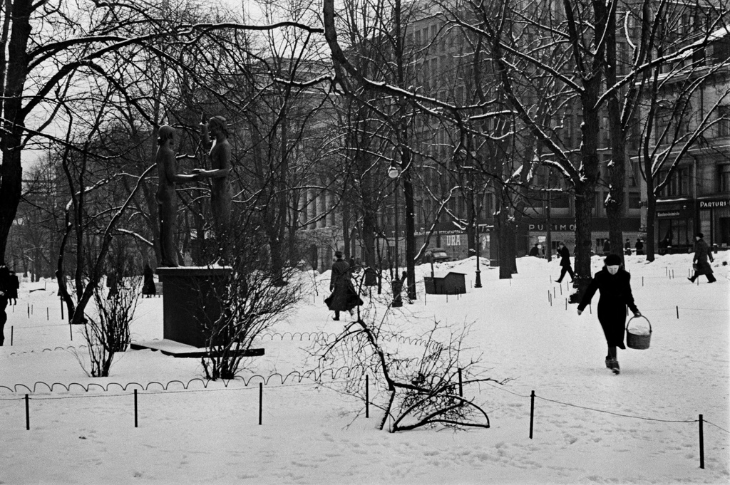 Teatteriesplanadi talvella, edessä vasemmalla Zacharias Topeliuksen muistomerkki Taru ja Totuus (Gunnar Finne, 1932), ympärillä jalankulkijoita. Taustalla Eteläinen Esplanaadikatu (=Eteläesplanadi) 12-20.