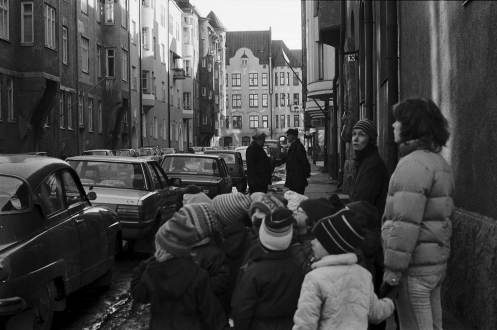 Luotsikatu. Vironniemen päiväkodin lapsiryhmä opettajineen on pysähtynyt Luotsikatu 10:n kohdalle katselemaan kadun varrella olevia jugend-rakennuksia. Näkymä Katajanokankadun kulmasta Vyökadun suuntaan. Tutustuminen Katajanokan vanhoihin ja uusiin rakennuksiin liittyi päiväkodissa kevätkaudella toteutettuun Viihtyisä ympäristö -projektiin.