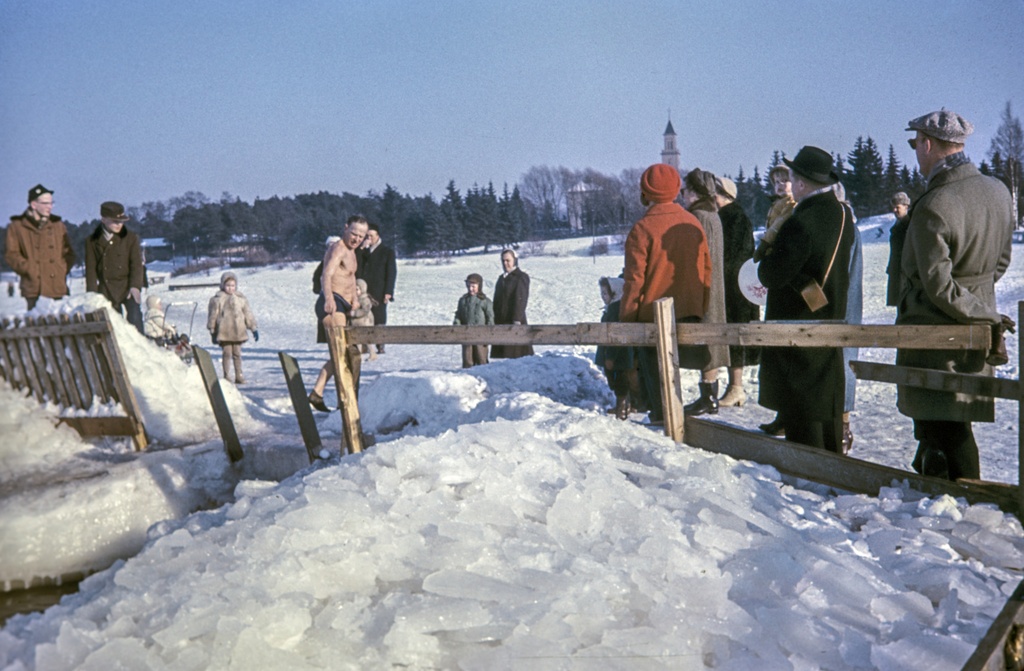 Seurasaarenselkä. Avantouimari ja ulkoilijoita avannon reunalla. Taustalla Hietaniemen hautausmaan uusi kappeli.