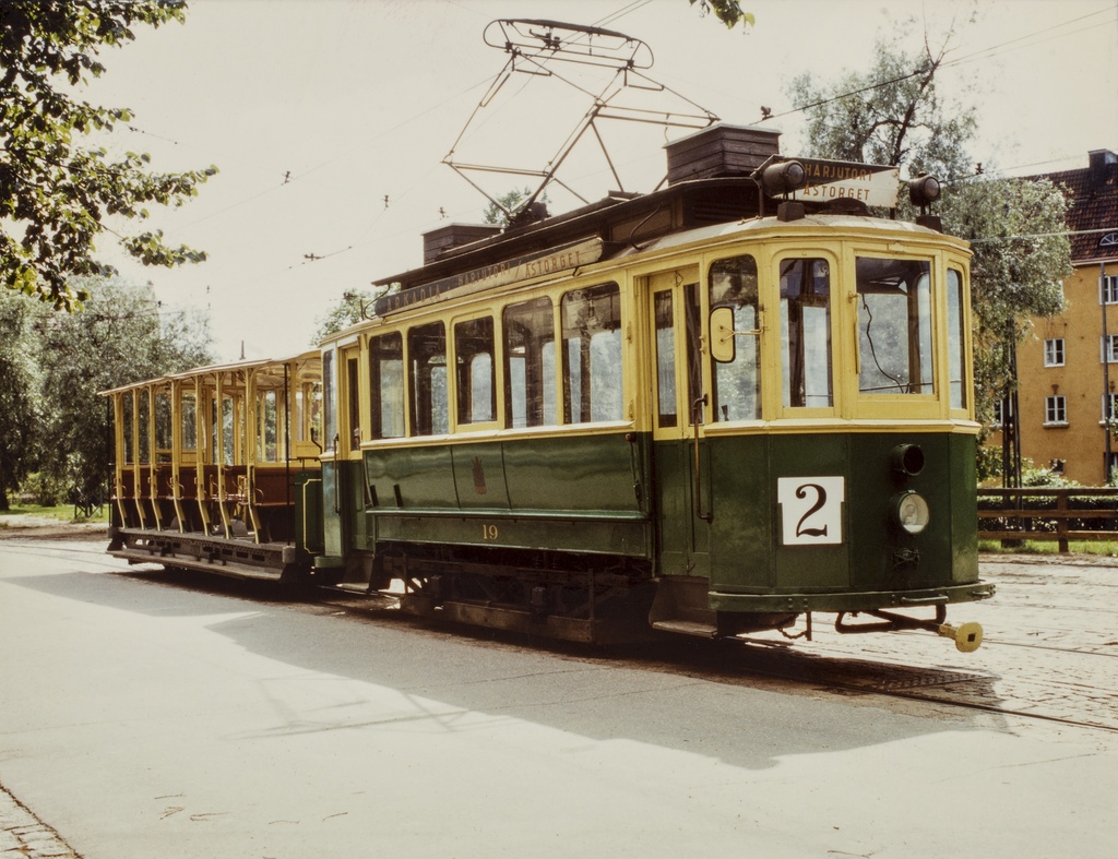 Vanha raitiovaunumallin esittely, moottorivaunu (Museovaunu HKL-19) ja avoin perävaunu Vallilan varikon ulkopuolella kesällä. Vaunussa lukee, Harjutori Åstorget ja se on linjalla 2.