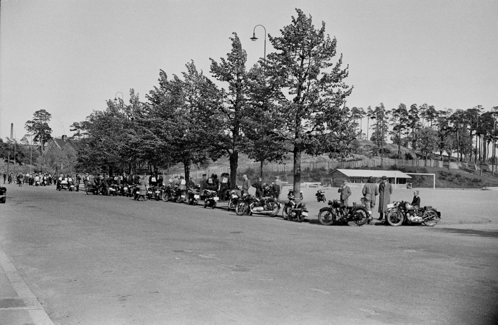 Moottoripyöräkilpailut, moottoripyöriä ja yleisöä Mäntymäentiellä, Messukentän (=Mäntymäenkenttä) reunalla.