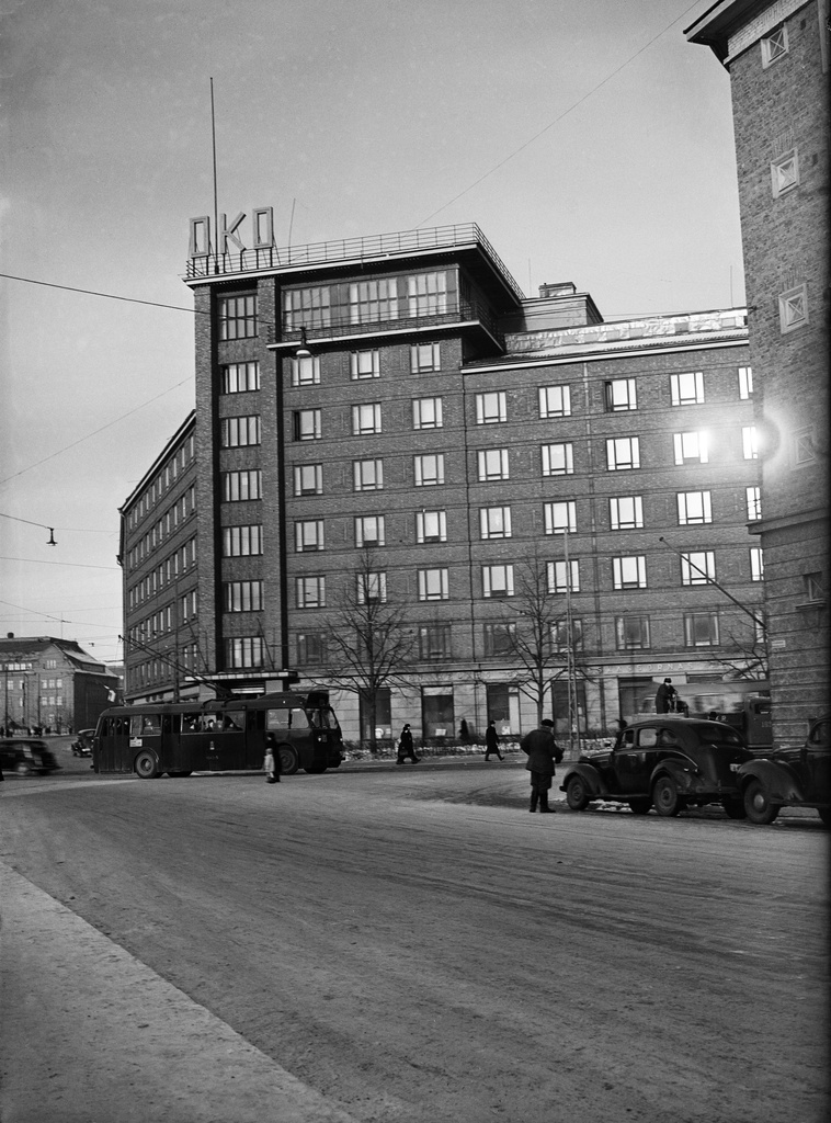 Näkymä Runeberginkadun ja Arkadiankadun risteyksestä pohjoiseen. Kuvan keskellä Osuuskassojen Keskusliiton rakennus, Arkadiankatu 23. Kadulla HKL:n johdinauto numero 604 linjalla 14, henkilöautoja ja takseja. Kuvan vasemmassa laidassa erottuu Tyttönormaalilyseon rakennus, Runeberginkatu 22-24.