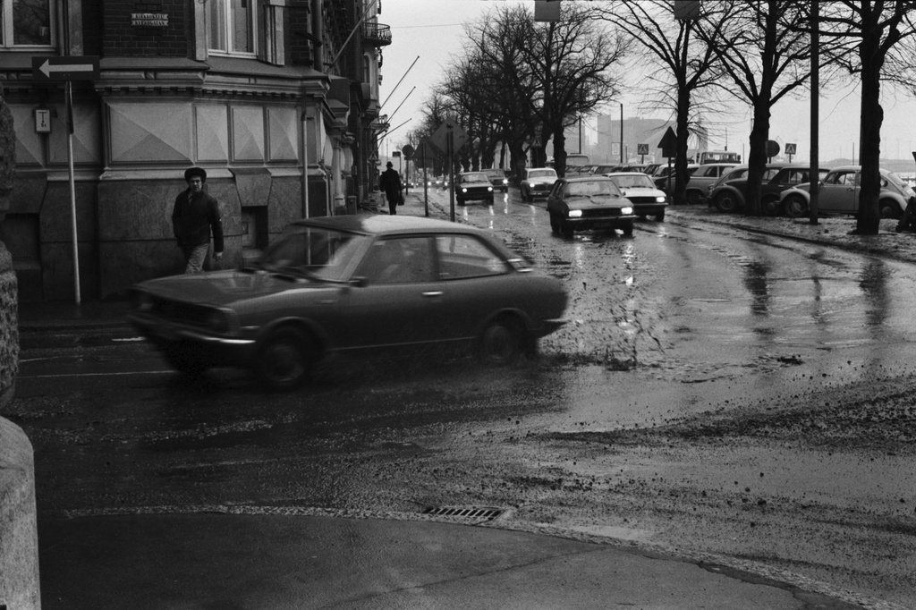 Pohjoisranta 6. Rapa roiskuu - liikennettä sadesäällä Pohjoisrannassa Kirkkokadun kulmassa. Näkymä Sörnäisten suuntaan.