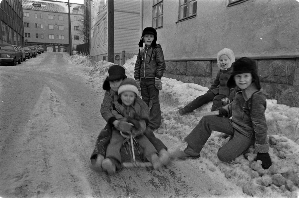 Lapsia Vanajantiellä Puu-Vallilassa. Kaksi poikaa laskee rattikelkalla mäkeä ajoradan puolella.